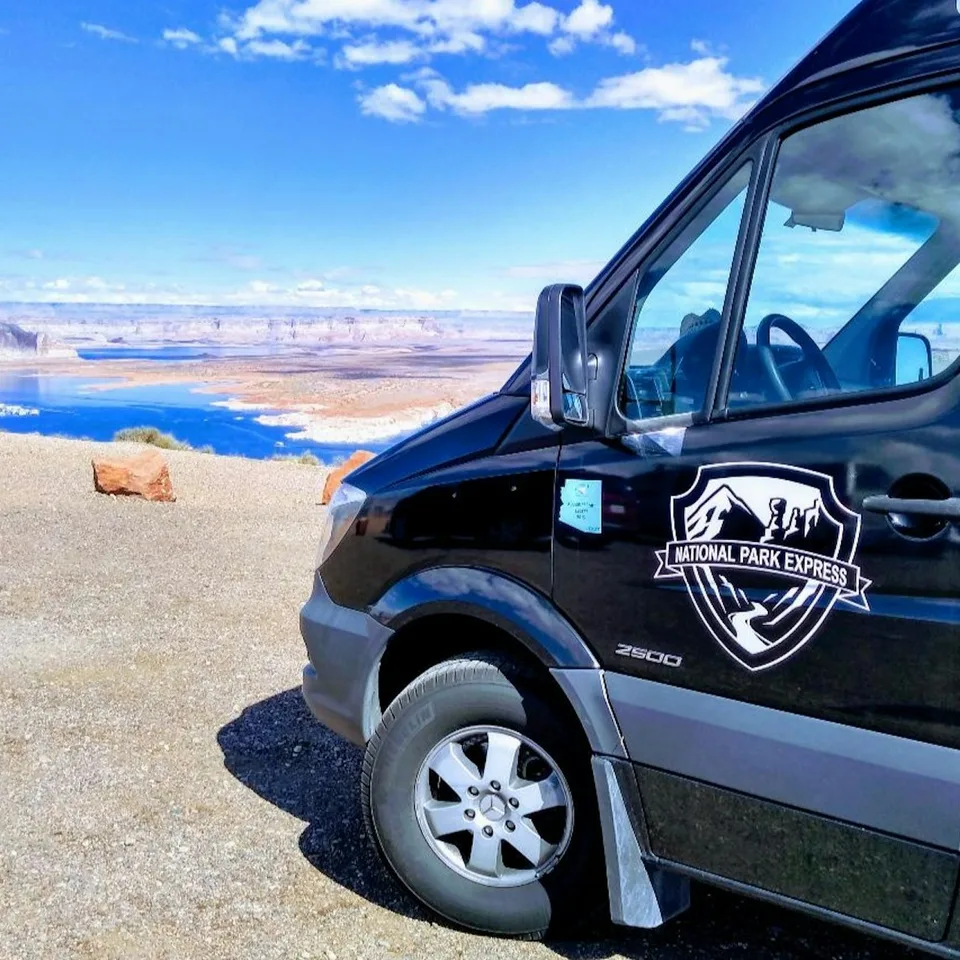 A shuttle vehicle parked beside a desert canyon viewpoint