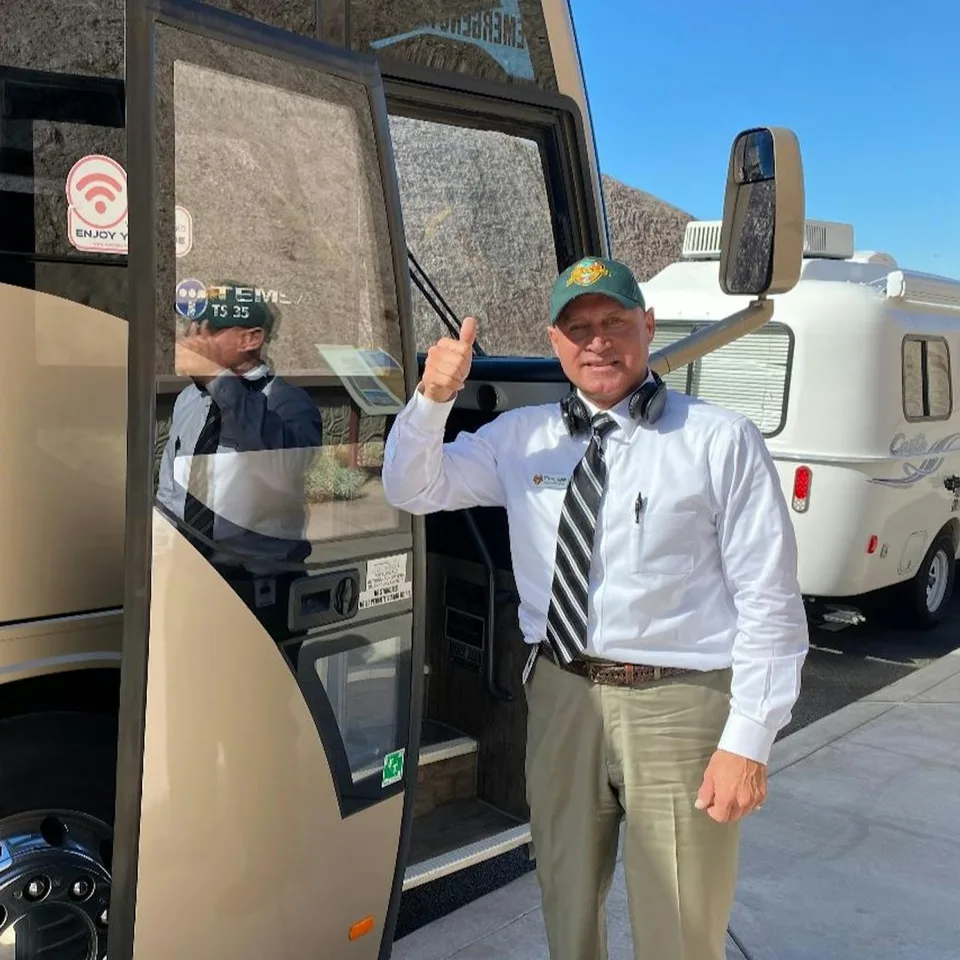 A driver beside the entrance to a shuttle coach