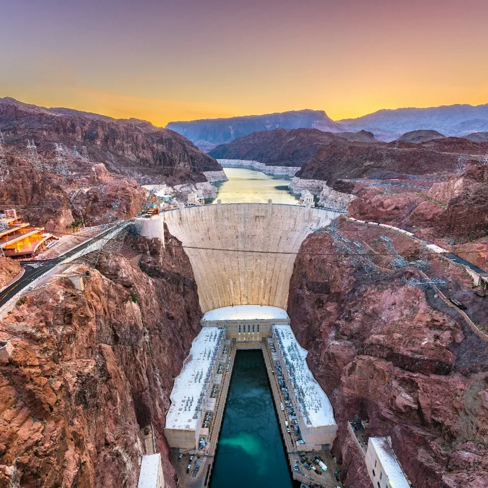 Hoover Dam and its bypass bridge seen from above at sunset