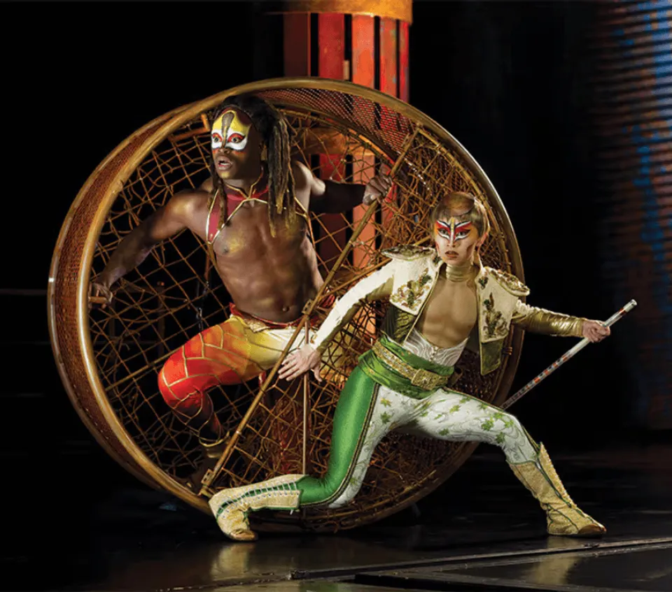 KÀ performers posing beside a large circular stage apparatus