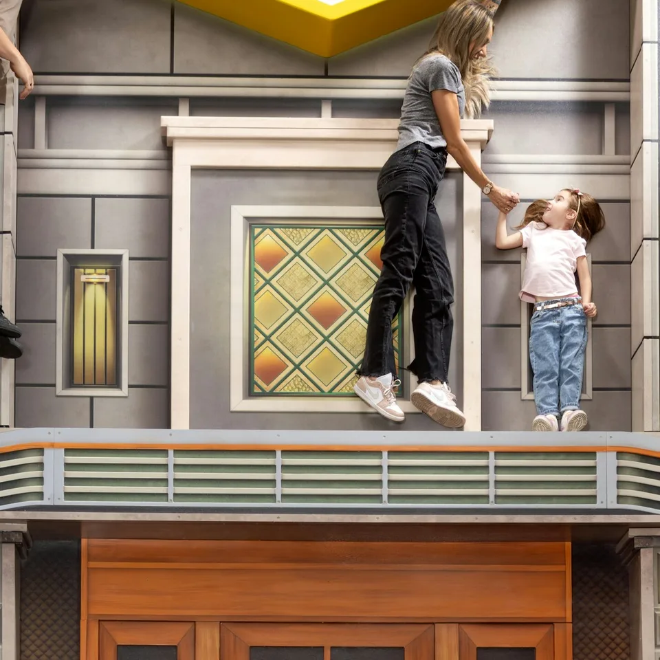 Visitors posing in a building-facade perspective illusion