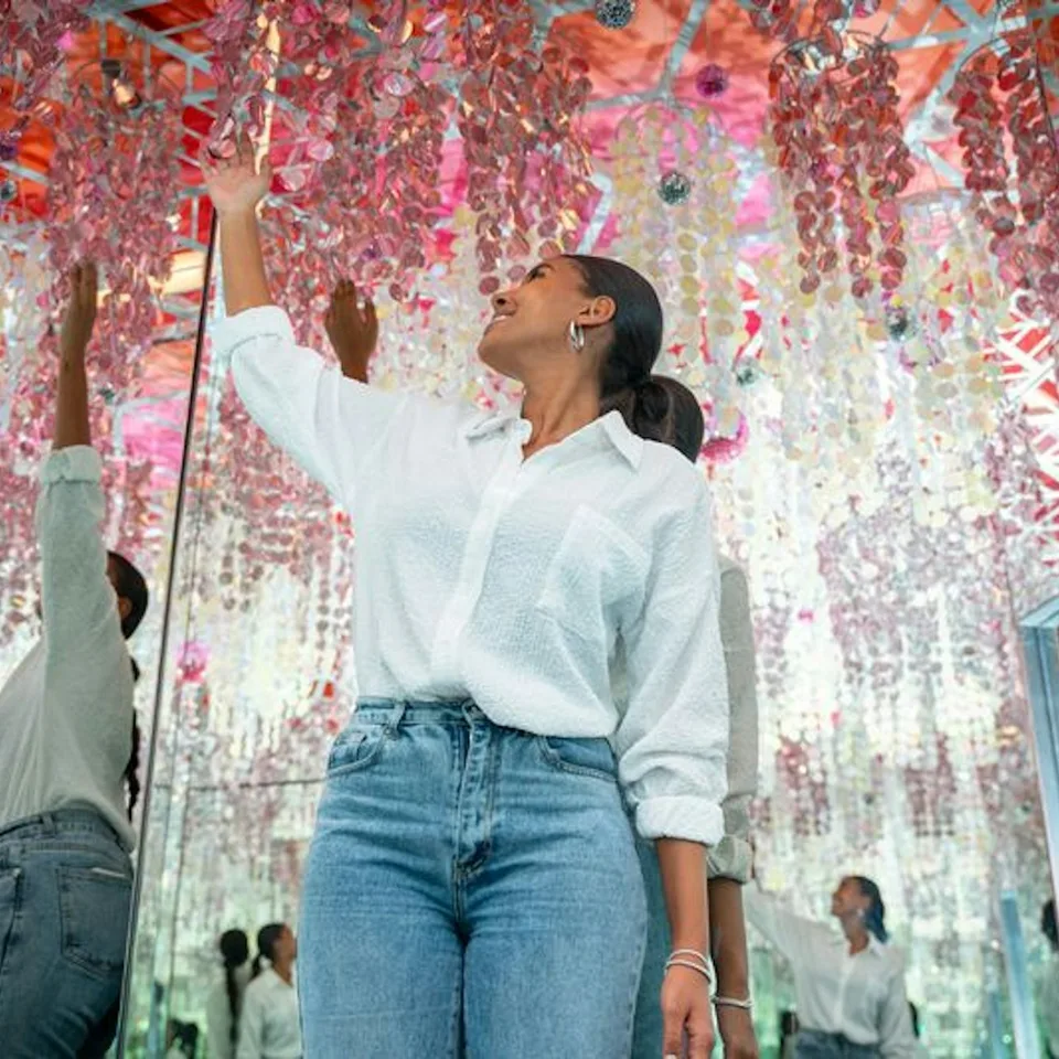 A visitor exploring a mirrored installation with red leaves
