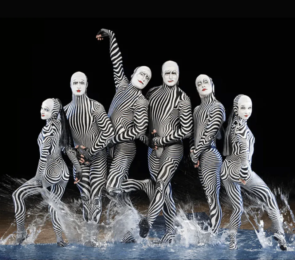 O performers in black and white costumes standing in the water