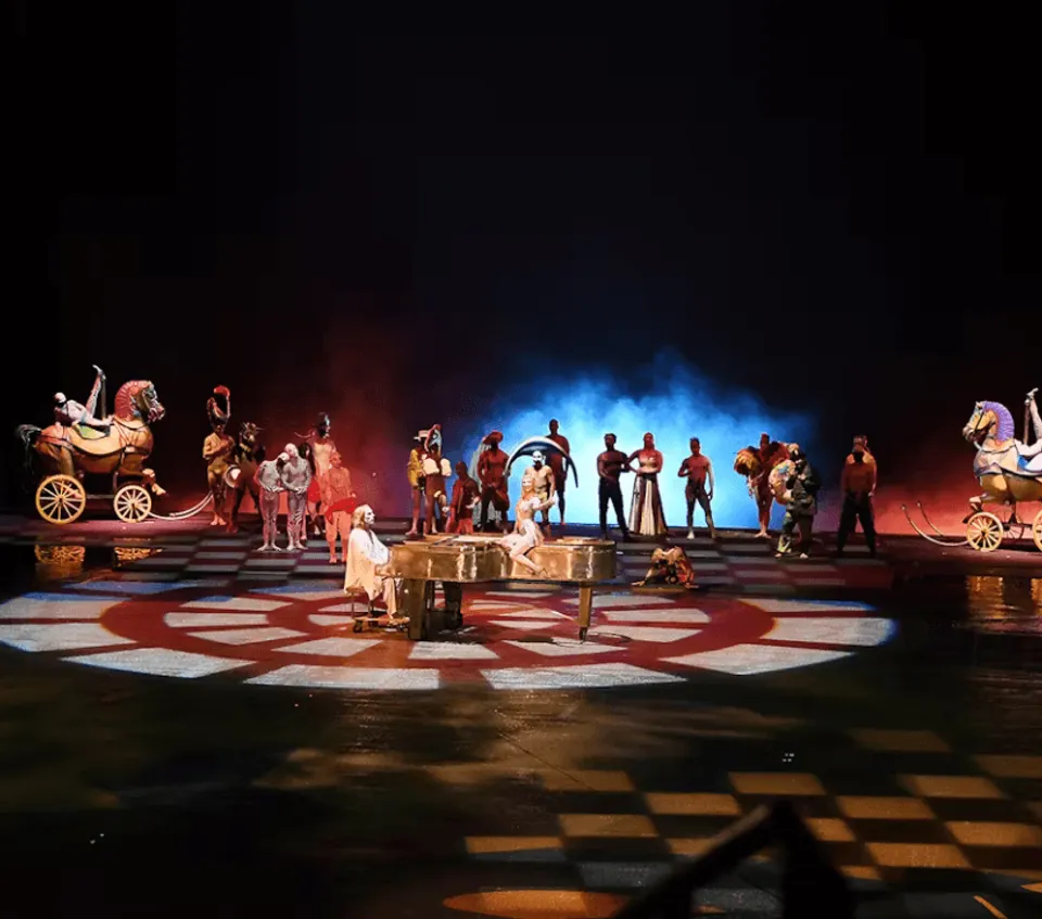 O ensemble gathered across the warmly lit stage