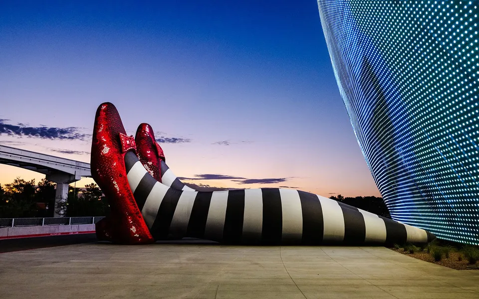 Ruby slipper and striped leg installation beside the illuminated Sphere exterior