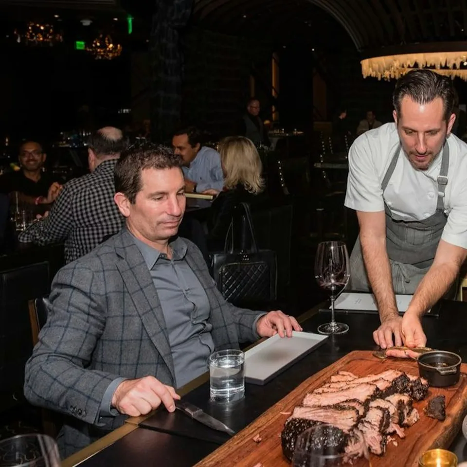 A diner watching steak being carved at a restaurant table