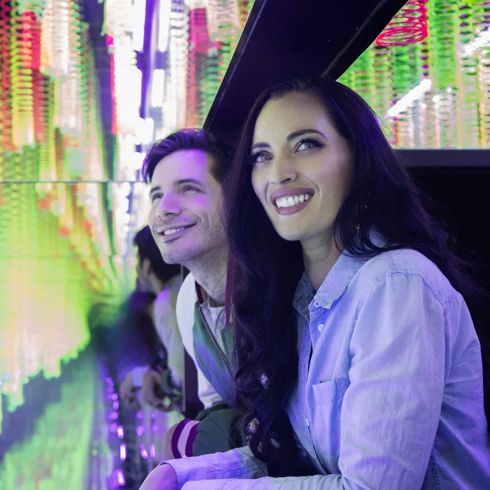 Visitors looking into a colourful reflected installation at Wink World