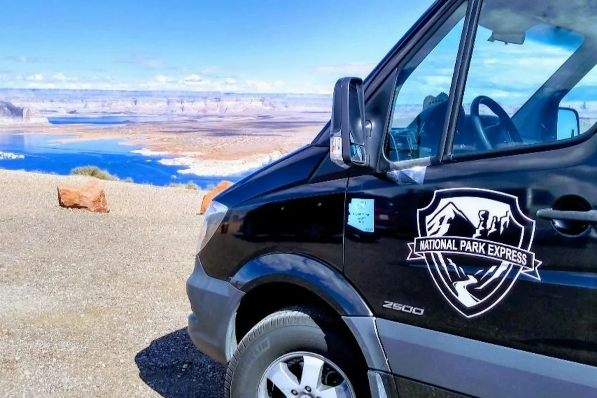 A shuttle vehicle parked beside a desert canyon viewpoint