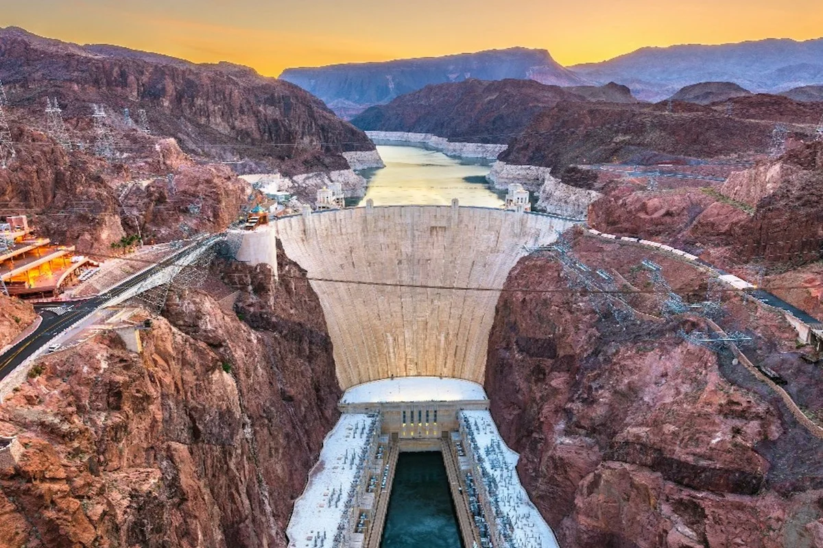 Hoover Dam and its bypass bridge seen from above at sunset