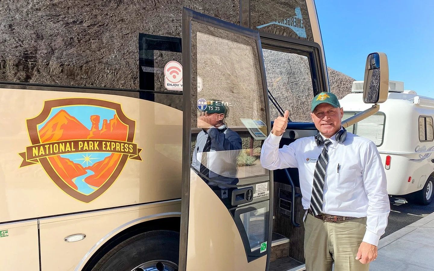Guide greeting visitors beside a Hoover Dam tour coach