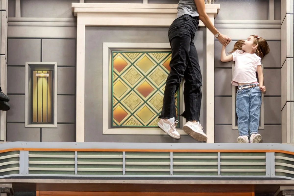 Visitors posing in a building-facade perspective illusion