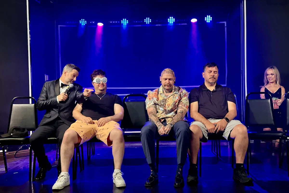 Steve Falcon with seated volunteers on a blue-lit stage